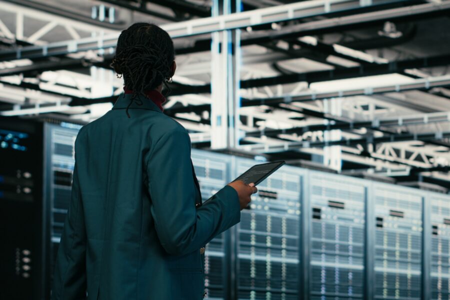 Woman standing in a data center looking at servers