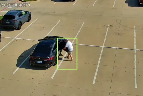 Flock generated surveillance video still. Guy opening a car door with a green targeting box around him